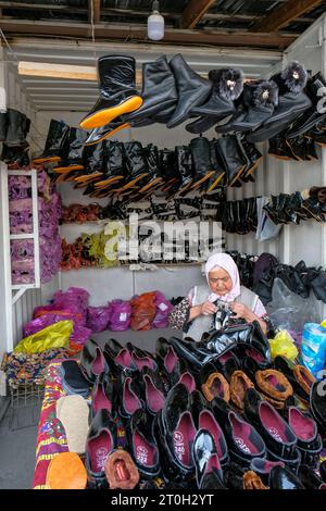 OSH, Kirgisistan - 6. Oktober 2023: Eine Frau, die Schuhe auf dem Jayma Basar in Osh, Kirgisistan verkauft. Stockfoto