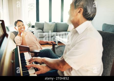 Glücklicher, Klavier und Senior-Mann, der im Wohnzimmer mit seiner Frau zur Musik spielt, um sich zu unterhalten, zu unterhalten oder Spaß zu haben. Instrument, Lächeln und ältere Asiaten Stockfoto