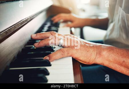 Hände, Klavier und Seniorenmann spielen für Musik im Wohnzimmer zur musikalischen Unterhaltungspraxis. Instrument, Hobby und ältere männliche Person in Stockfoto