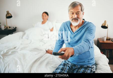Paare, Schlafzimmer oder Senioren schauen fernsehen oder streamen Filme über ein Abonnement, um sich im gemeinsamen Urlaub zu entspannen. Lächeln, Fernsehen oder reife Frau Stockfoto