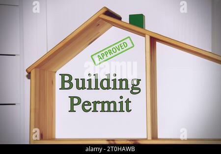 Hausmodell mit dem Text ‚Baugenehmigung‘ und dem genehmigten Stempel. Stockfoto