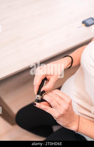 Junge schwangere Brünette, die einen Schwangerschaftsdiabetes-Selbsttest zur Zuckerkontrolle durchführt. Blutungen am Finger Stockfoto