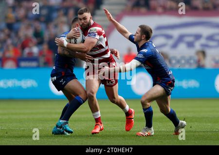 Wigan Warriors’ Kaide Ellis (Mitte) wird im Halbfinalspiel der Betfred Super League im DW Stadium in Wigan von Elliot Minchella (links) und Kane Linnett von Hull KR (links) angegriffen. Bilddatum: Samstag, 7. Oktober 2023. Stockfoto