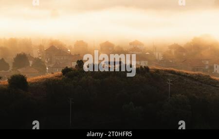 Kleine Taxifahrt auf einem Hügel mit magischem und atemberaubendem Hintergrundnebel über dem Dorf. Stockfoto