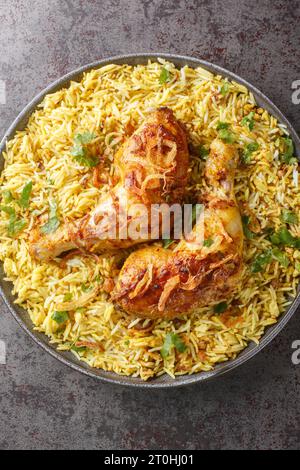 Bangladeshi würziges gebratenes Huhn mit aromatischem Pilaw in Nahaufnahme auf einem Teller auf dem Tisch. Vertikale Draufsicht von oben Stockfoto