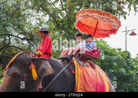 Ayutthaya, Thailand - 1. August 2023: Kinder reiten auf einem Elefanten auf der Straße der Stadt. Dies ist eine beliebte Unterhaltung für Besucher von Ayutthaya. Stockfoto