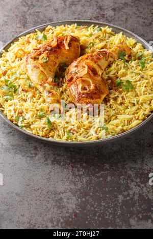 Bangladeshi würziges gebratenes Huhn mit aromatischem Pilaw in Nahaufnahme auf einem Teller auf dem Tisch. Vertikal Stockfoto