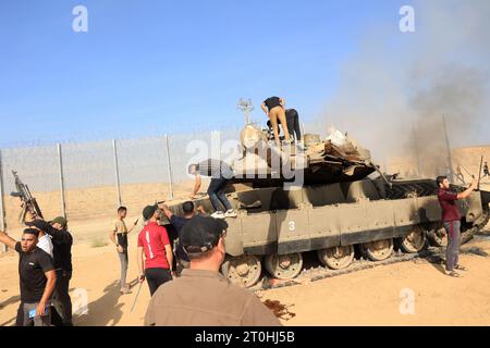 Rafah, Gaza. Oktober 2023. Die Palästinenser übernehmen die Kontrolle über einen israelischen Panzer, nachdem sie am Samstag, 7. Oktober 2023, den Grenzzaun mit Israel von Khan Yunis im südlichen Gazastreifen überquert haben. Während Militante der blockierten palästinensischen Enklave Israel infiltrierten, wurden in der Morgenröte Raketenfluten aus dem Gazastreifen auf Israel abgefeuert. Foto: Ismael Mohamad/UPI. Quelle: UPI/Alamy Live News Stockfoto