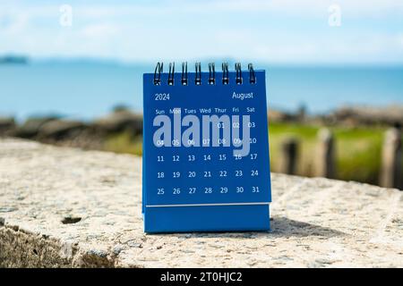 Blauer August-Kalender 2024 auf verschwommenem Hintergrund des blauen Ozeans. Neujahrskonzept 2024 Stockfoto