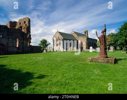 Sehen Sie SW einer Zement- und Sandsteinstatue von St. Aidan, die 1958 von der Bildhauerin Kathleen Parbury in St. Mary's Kirchhof, Holy Island, Großbritannien, angefertigt wurde Stockfoto