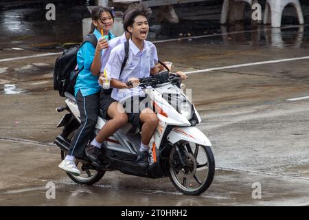 SAMUT PRAKAN, THAILAND, Juni 06 2023, Ein Trio fröhlicher Teenager, Die im Regen mit dem Motorrad fahren Stockfoto