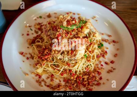 Dünne Nudeln mit Kräutern, Speck, Knoblauch und Chili auf einem weißen Teller Stockfoto
