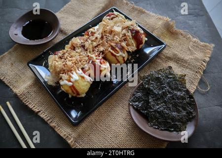 Takoyaki ist ein japanisches Essen, das aus Weizenmehlteig, Oktopusfleisch oder anderen Füllungen hergestellt wird, serviert mit Sauce, Mayonnaise und Topping in Form von Ka Stockfoto