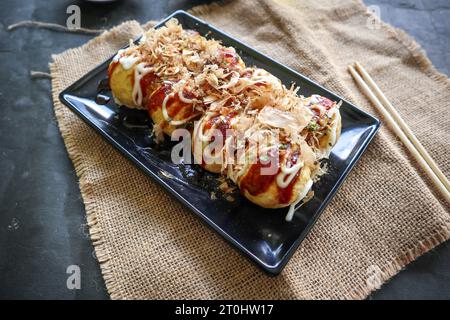 Takoyaki ist ein japanisches Essen, das aus Weizenmehlteig, Oktopusfleisch oder anderen Füllungen hergestellt wird, serviert mit Sauce, Mayonnaise und Topping in Form von Ka Stockfoto