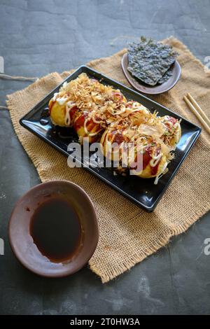 Takoyaki ist ein japanisches Essen, das aus Weizenmehlteig, Oktopusfleisch oder anderen Füllungen hergestellt wird, serviert mit Sauce, Mayonnaise und Topping in Form von Ka Stockfoto