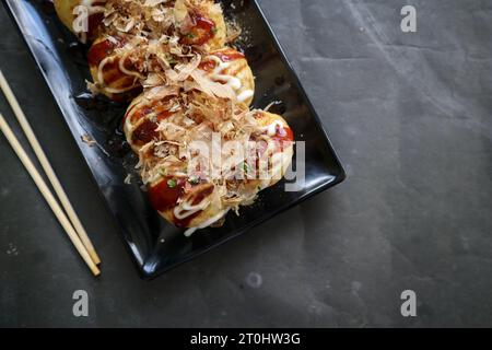 Takoyaki ist ein japanisches Essen, das aus Weizenmehlteig, Oktopusfleisch oder anderen Füllungen hergestellt wird, serviert mit Sauce, Mayonnaise und Topping in Form von Ka Stockfoto