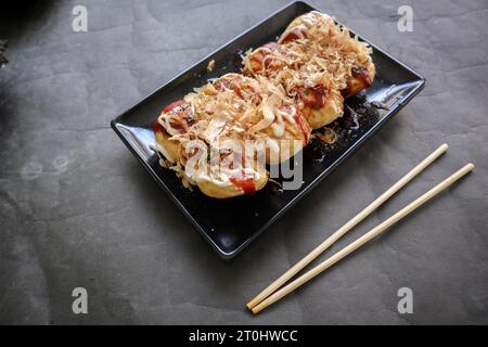 Takoyaki ist ein japanisches Essen, das aus Weizenmehlteig, Oktopusfleisch oder anderen Füllungen hergestellt wird, serviert mit Sauce, Mayonnaise und Topping in Form von Ka Stockfoto