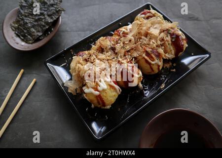 Takoyaki ist ein japanisches Essen, das aus Weizenmehlteig, Oktopusfleisch oder anderen Füllungen hergestellt wird, serviert mit Sauce, Mayonnaise und Topping in Form von Ka Stockfoto