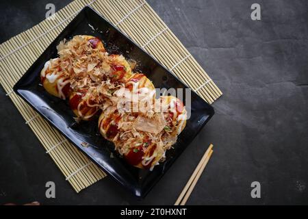 Takoyaki ist ein japanisches Essen, das aus Weizenmehlteig, Oktopusfleisch oder anderen Füllungen hergestellt wird, serviert mit Sauce, Mayonnaise und Topping in Form von Ka Stockfoto