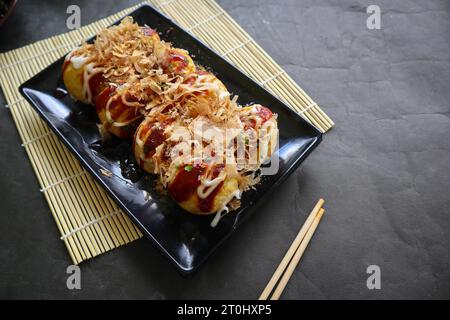 Takoyaki ist ein japanisches Essen, das aus Weizenmehlteig, Oktopusfleisch oder anderen Füllungen hergestellt wird, serviert mit Sauce, Mayonnaise und Topping in Form von Ka Stockfoto