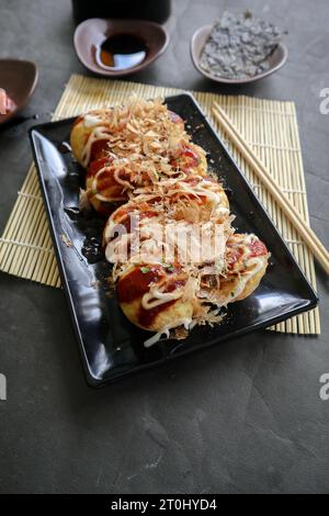 Takoyaki ist ein japanisches Essen, das aus Weizenmehlteig, Oktopusfleisch oder anderen Füllungen hergestellt wird, serviert mit Sauce, Mayonnaise und Topping in Form von Ka Stockfoto