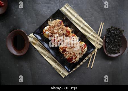 Takoyaki ist ein japanisches Essen, das aus Weizenmehlteig, Oktopusfleisch oder anderen Füllungen hergestellt wird, serviert mit Sauce, Mayonnaise und Topping in Form von Ka Stockfoto