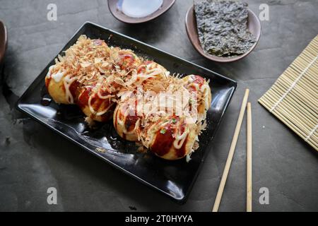 Takoyaki ist ein japanisches Essen, das aus Weizenmehlteig, Oktopusfleisch oder anderen Füllungen hergestellt wird, serviert mit Sauce, Mayonnaise und Topping in Form von Ka Stockfoto