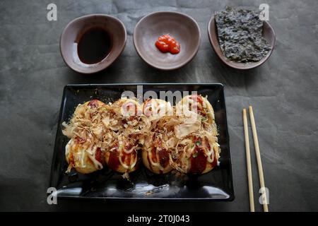 Takoyaki ist ein japanisches Essen, das aus Weizenmehlteig, Oktopusfleisch oder anderen Füllungen hergestellt wird, serviert mit Sauce, Mayonnaise und Topping in Form von Ka Stockfoto