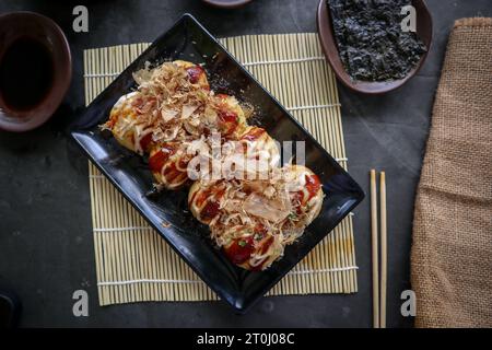 Takoyaki ist ein japanisches Essen, das aus Weizenmehlteig, Oktopusfleisch oder anderen Füllungen hergestellt wird, serviert mit Sauce, Mayonnaise und Topping in Form von Ka Stockfoto