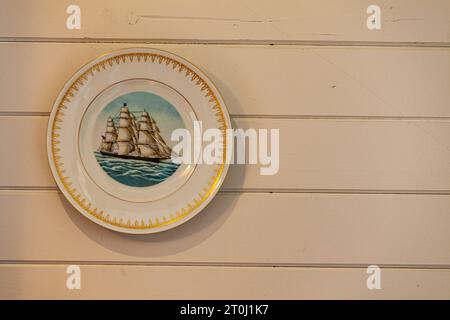 Dekorative Platte hängt an einer bemalten hölzernen Innenwand in Steveston, British Columbia, Kanada Stockfoto