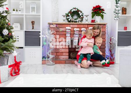 Die liebende Mutter hält ihre Tochter und ihren Sohn auf ihrem Schoß Stockfoto
