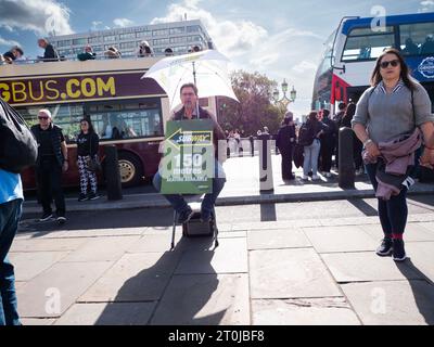 Mann mit Sandwich-Schild und Regenschirm an der Westminster Bridge London, Werbung für das Subway Restaurant, unter Pendlern und Touristen Stockfoto
