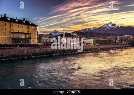 Goldener Sonnenuntergang in Innsbruck. Dramatischer Abendhimmel in Österreich. Wahrzeichen von Innsbuck. Flussdamm in Tirol. Winter wunderschöne Stadtlandschaft. Weihnachten. Stockfoto