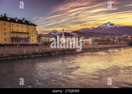 Goldener Sonnenuntergang in Innsbruck. Dramatischer Abendhimmel in Österreich. Wahrzeichen von Innsbuck. Flussdamm in Tirol. Winter wunderschöne Stadtlandschaft. Weihnachten. Stockfoto