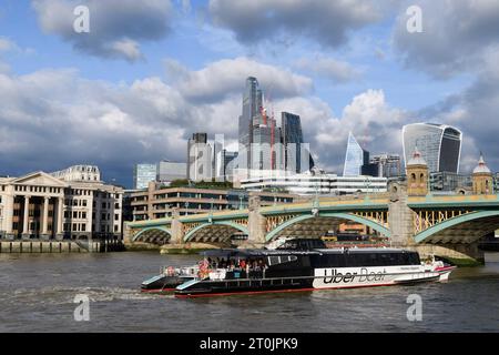 Ein Uber-Boot mit der Marke Thames Clippers passiert die Southwark Bridge über die Themse mit den Wolkenkratzern des Finanzviertels City of London in t Stockfoto