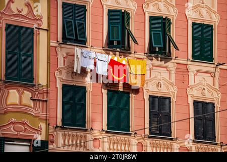 Ein historisches altes Haus in Europa, das in der heißen Sommersonne Kleidung an einem Wäscheleinen vom Fenster aus trocknet. Stockfoto