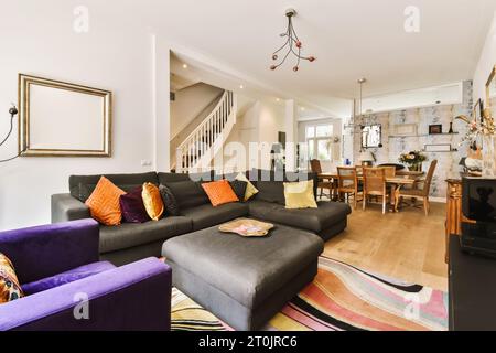 Ein Wohnzimmer mit lila Sofas und bunten Teppichen in der Mitte des Zimmers ist eine offene Treppe Stockfoto