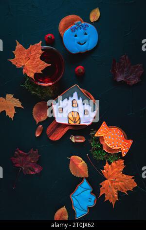 Herbsttee. Tasse Tee, bemalte Lebkuchen, Eicheln und Blätter auf schwarzem Hintergrund. Stockfoto