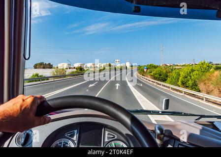 Blick von der Fahrposition eines Lkws auf eine Straße, die zu einigen Fabriklagern führt. Stockfoto