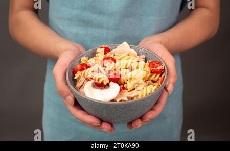 Nudelsalat in einer Schüssel, in Scheiben geschnittene Pilze, Tomaten, rote Pfefferstücke und Thunfisch, gesunde Lebensmittel mit Gemüse, frische Bio-Ernährung Stockfoto