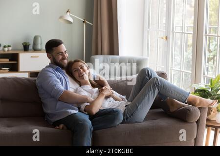 Glückliches freudiges Dating-Paar, das sich im Wohnzimmer entspannt Stockfoto