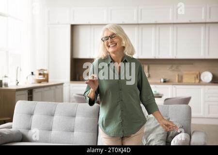 Freudig aufgeregte blonde Seniorin in Brille, die Bewegung genießt Stockfoto