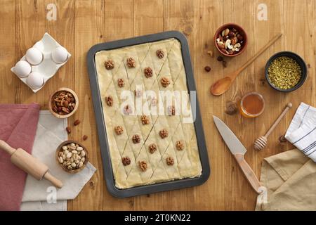 Ich mache köstliche Baklava. Backpfanne mit Teig und Zutaten auf Holztisch, flach liegend Stockfoto