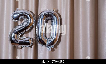 20 Metallballon isoliert auf Altas Textil Hintergrund. Grußkarte Silberfolie Ballonnummer Happy Birthday Holiday Konzept. Kopierbereich für Text. Feier Party Glückwunschdekoration Stockfoto