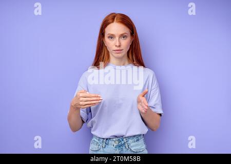 Selbstbewusste attraktive rothaarige Frau mit Fingerbuchstaben. Nahaufnahme Porträt isolierter blauer Hintergrund, Frau mit Nummer 400 Stockfoto