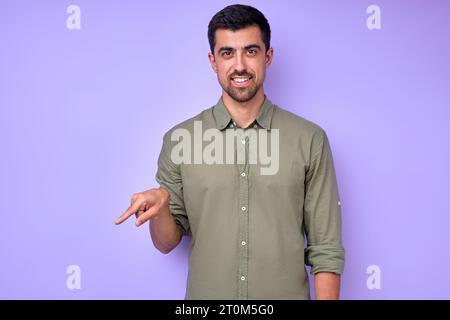 Fröhlicher brünette bärtiger Mann, der den Buchstaben Q q demonstriert. Gebärdensprachsymbol für Tauben Menschen auf blauem Hintergrund. Isoliert Stockfoto