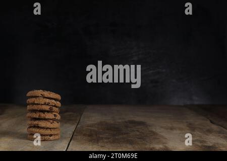 Stapel Schokoladenkekse auf Holztisch auf schwarzem Hintergrund Stockfoto