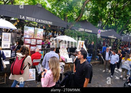 Touristen, die Kunstwerke verschiedener Künstler am Place Tertre im Pariser Montmartre besichtigen Stockfoto