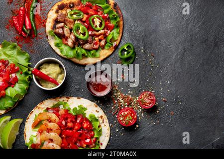 Tacos mit Salsa, Gemüse und Avocado auf schwarzem Hintergrund. Kopierbereich. Stockfoto