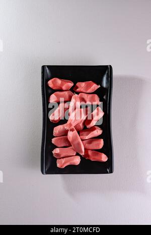 Ungewöhnliche und köstliche geometrische Würstchen auf einem schwarzen Teller. Chinesische Küche, Hotpot-Zutat Stockfoto